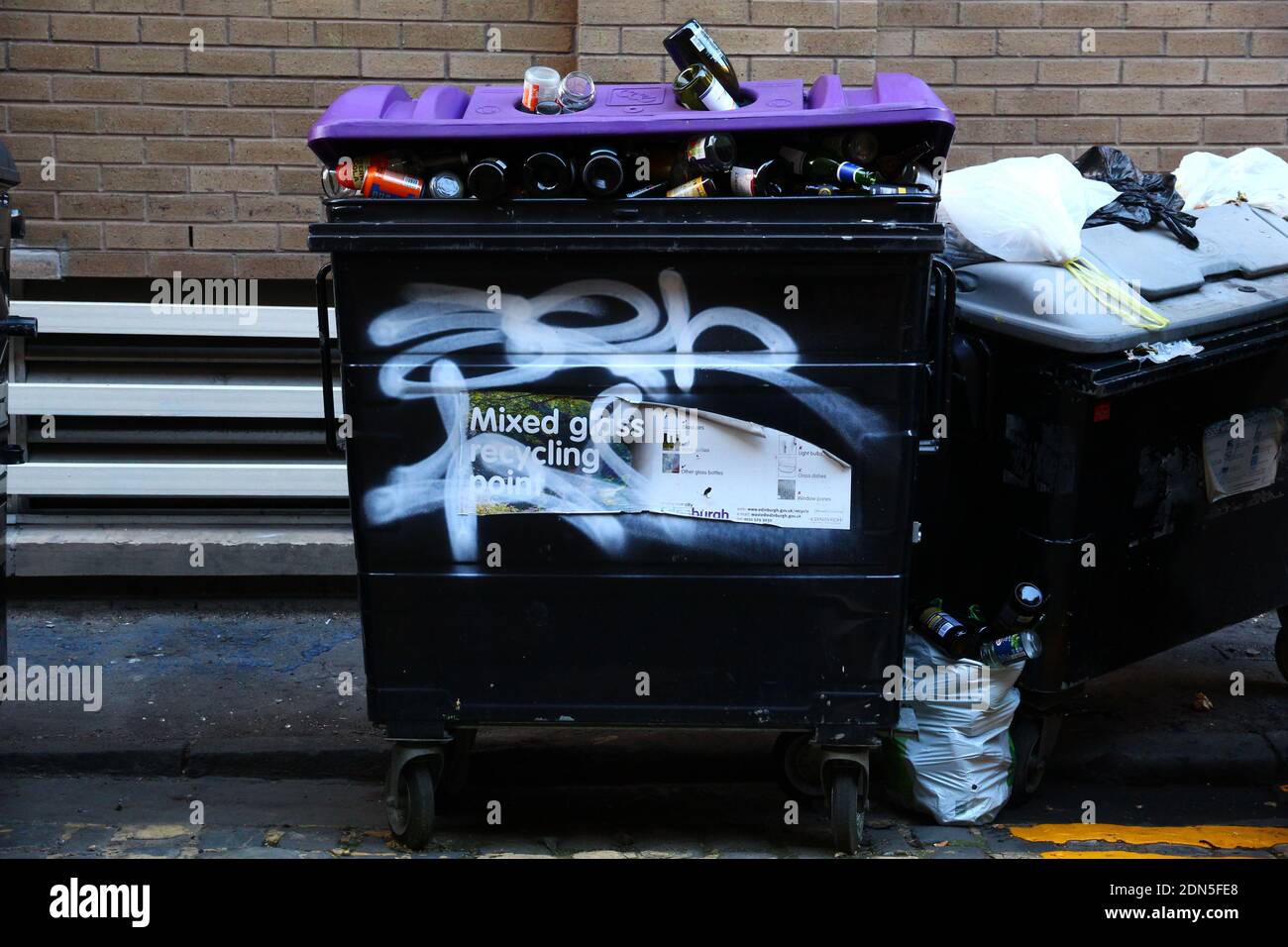 Conteneur de recyclage de bouteilles en verre débordant dans une allée arrière Banque D'Images