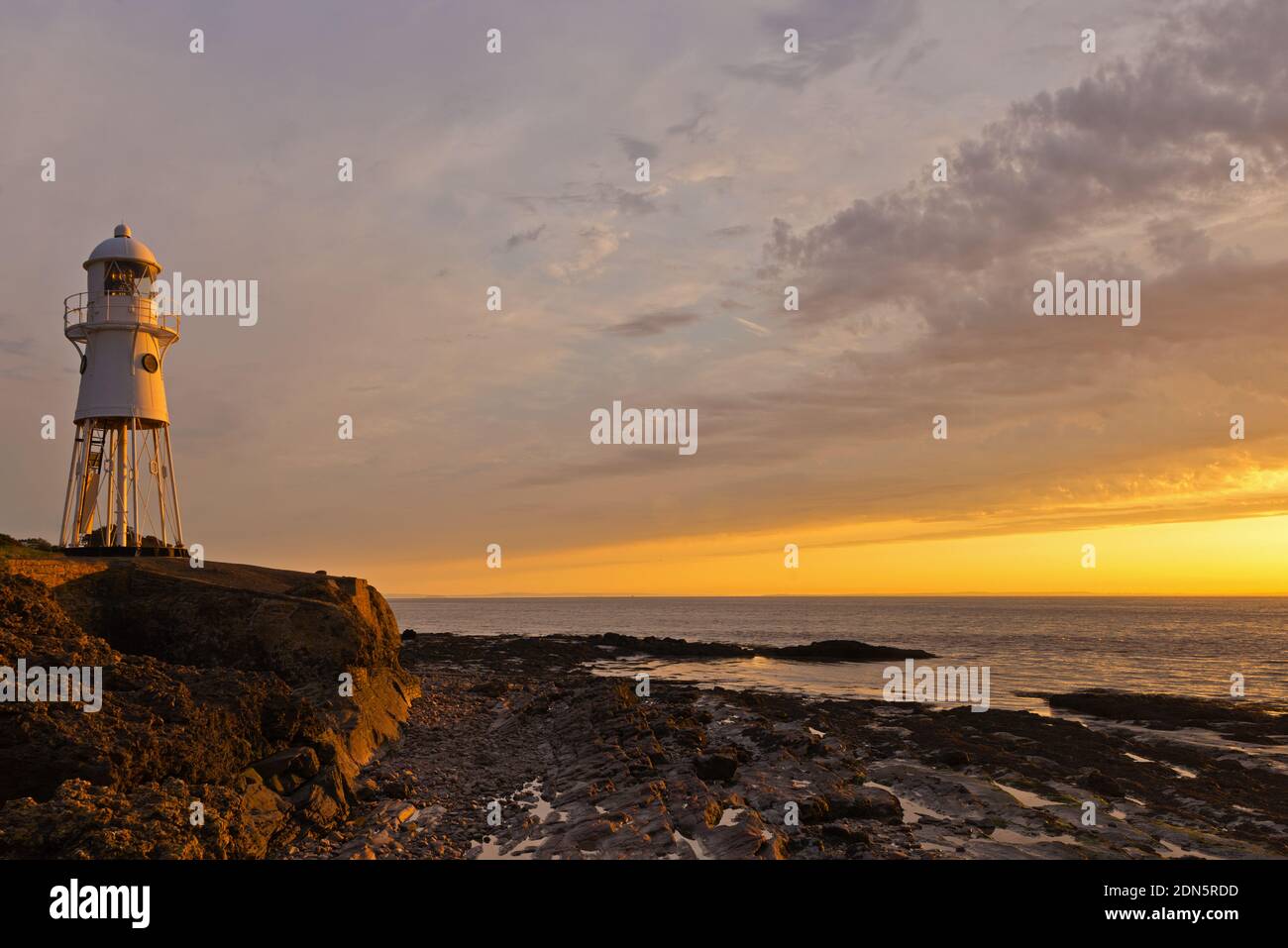 Une photo de coucher de soleil avec le phare de Black Nore surplombant le canal de Bristol sur la côte près de Portishead, Somerset, Angleterre, Royaume-Uni. Banque D'Images