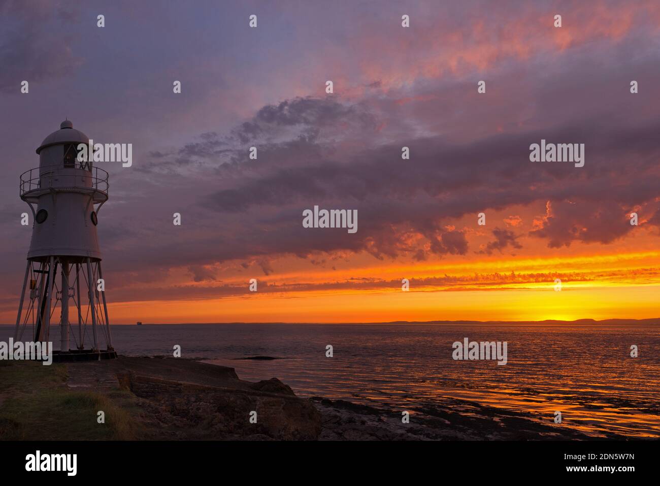 Une photo de coucher de soleil avec le phare de Black Nore surplombant le canal de Bristol sur la côte près de Portishead, Somerset, Angleterre, Royaume-Uni. Banque D'Images