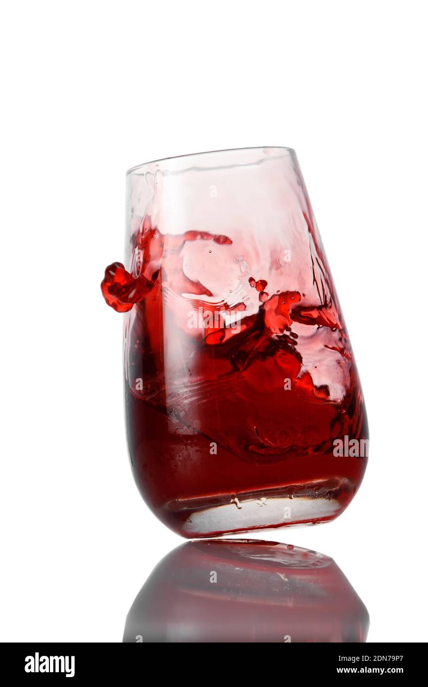 La limonade rouge éclabousse le verre sur fond blanc Banque D'Images