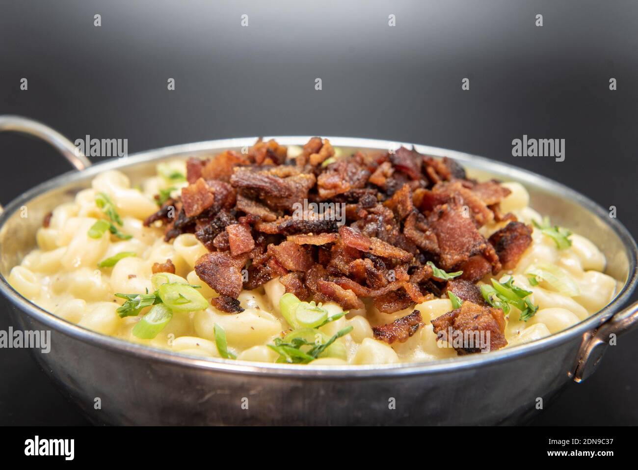 Bol de macaroni au fromage avec une pile généreuse de morceaux de bacon pour plus de saveur sur le dessus. Banque D'Images