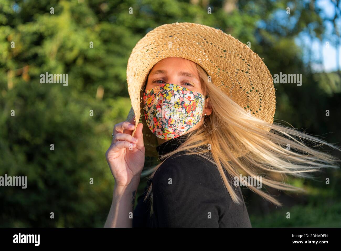 Belle jeune femme portant un masque facial coronavirus couvrant avec un motif floral pendant le verrouillage pandémique Covid-19 Banque D'Images
