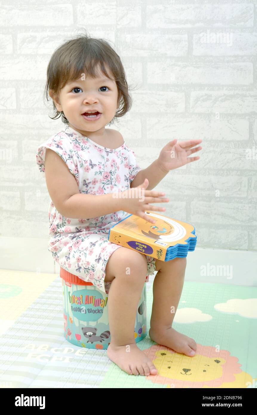 bébé fille de 2 ans tredller, palying avec des livres. Lecture d'un livre Banque D'Images