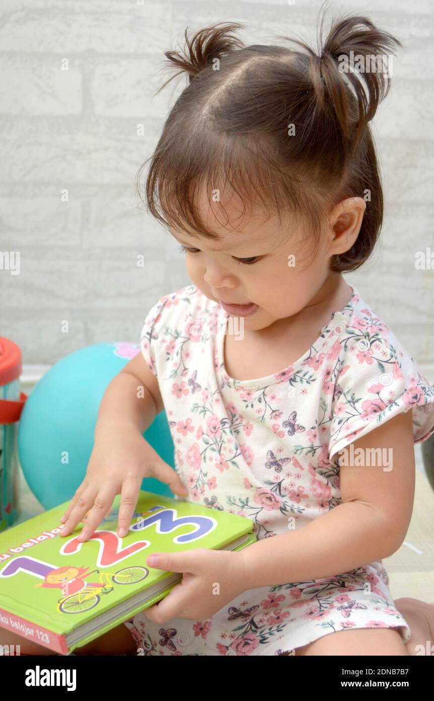 bébé fille de 2 ans tredller, palying avec des livres. Lecture d'un livre Banque D'Images