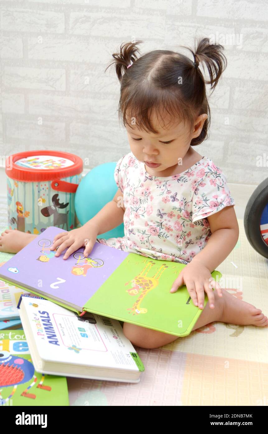 bébé fille de 2 ans tredller, palying avec des livres. Lecture d'un livre Banque D'Images
