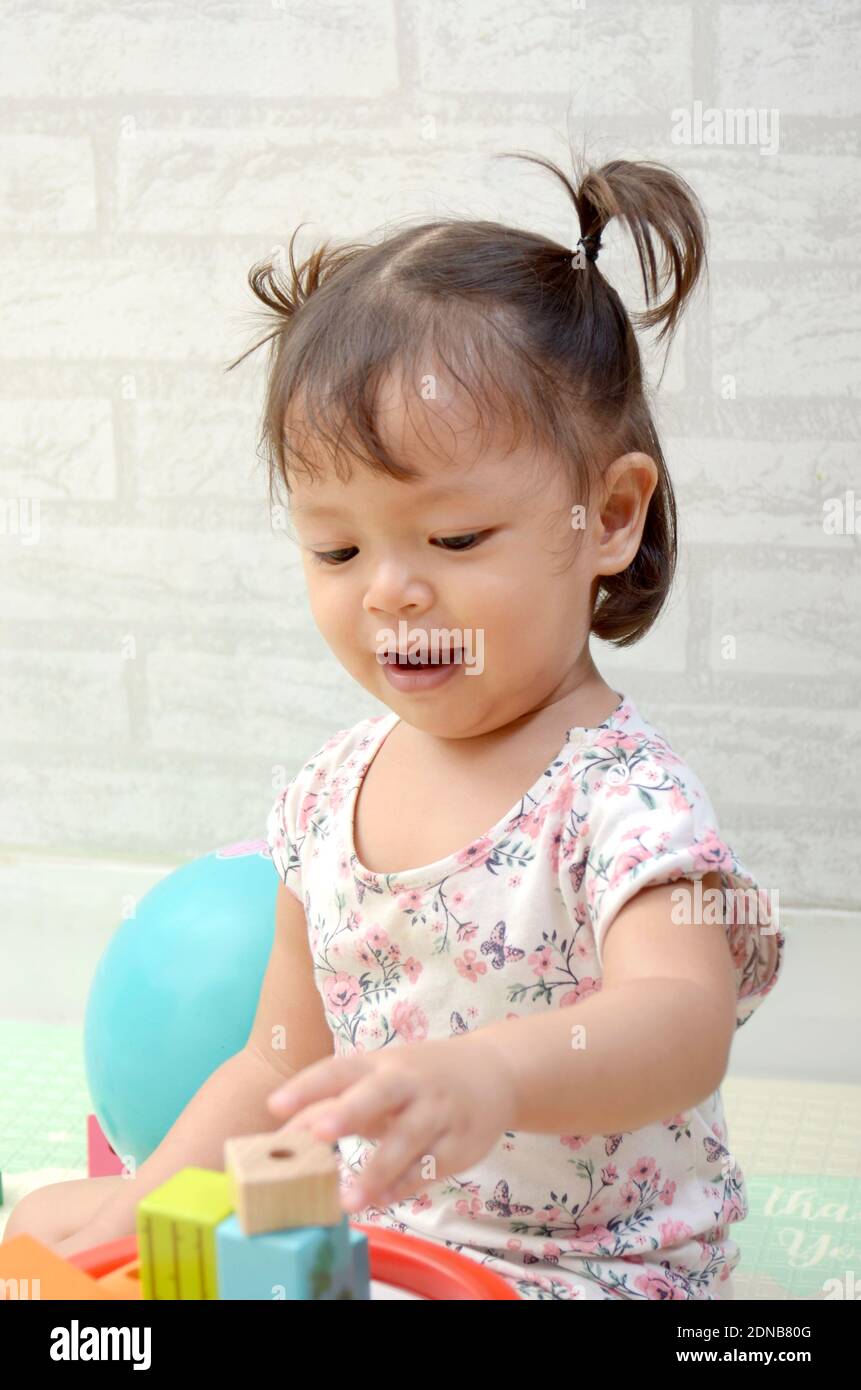 Petite fille, 2 ans, jouant de bloc de bois coloré Banque D'Images