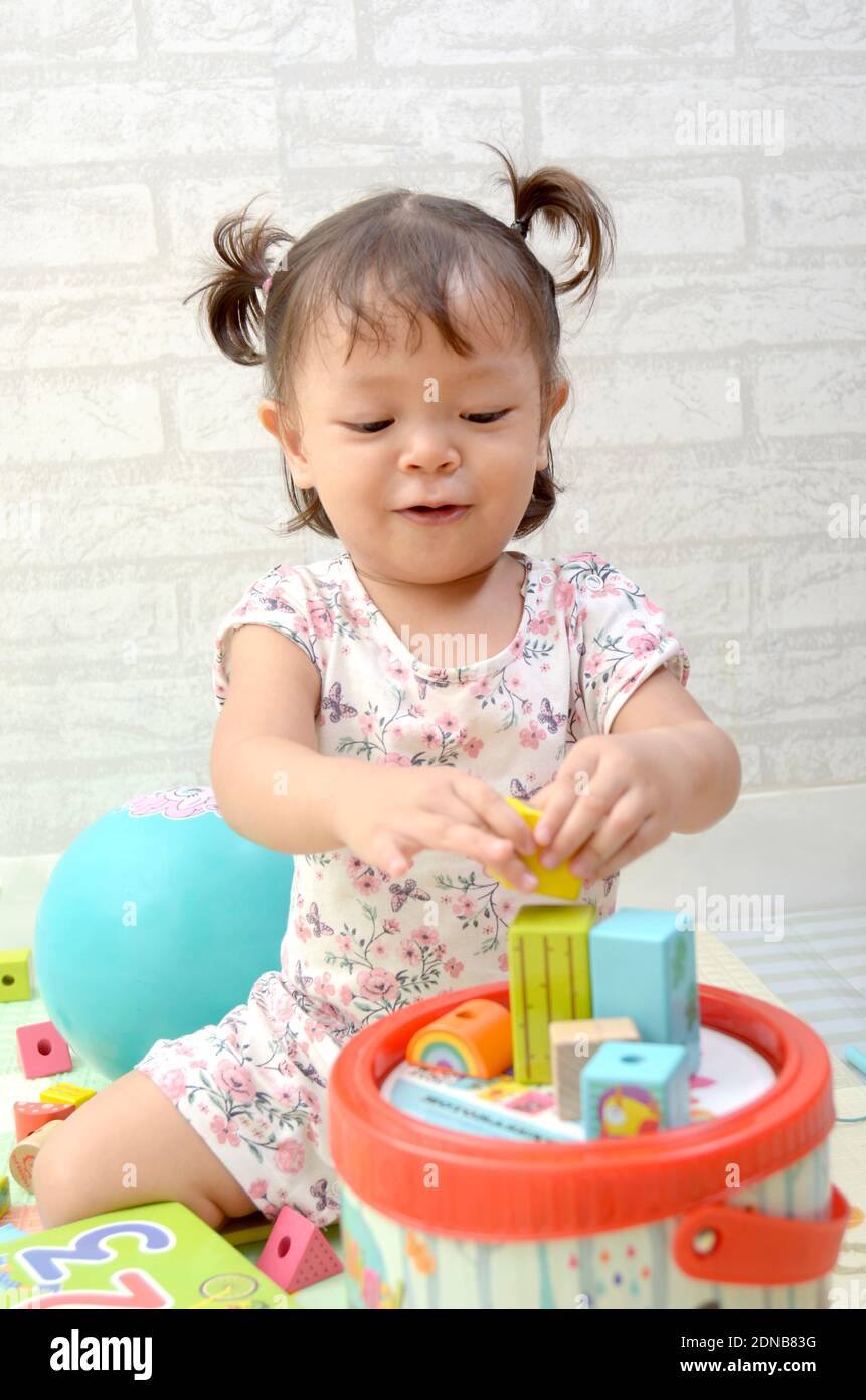 Petite fille, 2 ans, jouant de bloc de bois coloré Banque D'Images