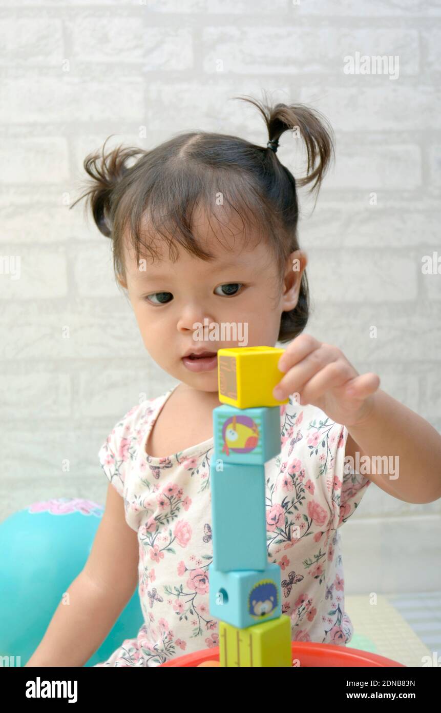 Petite fille, 2 ans, jouant de bloc de bois coloré Banque D'Images