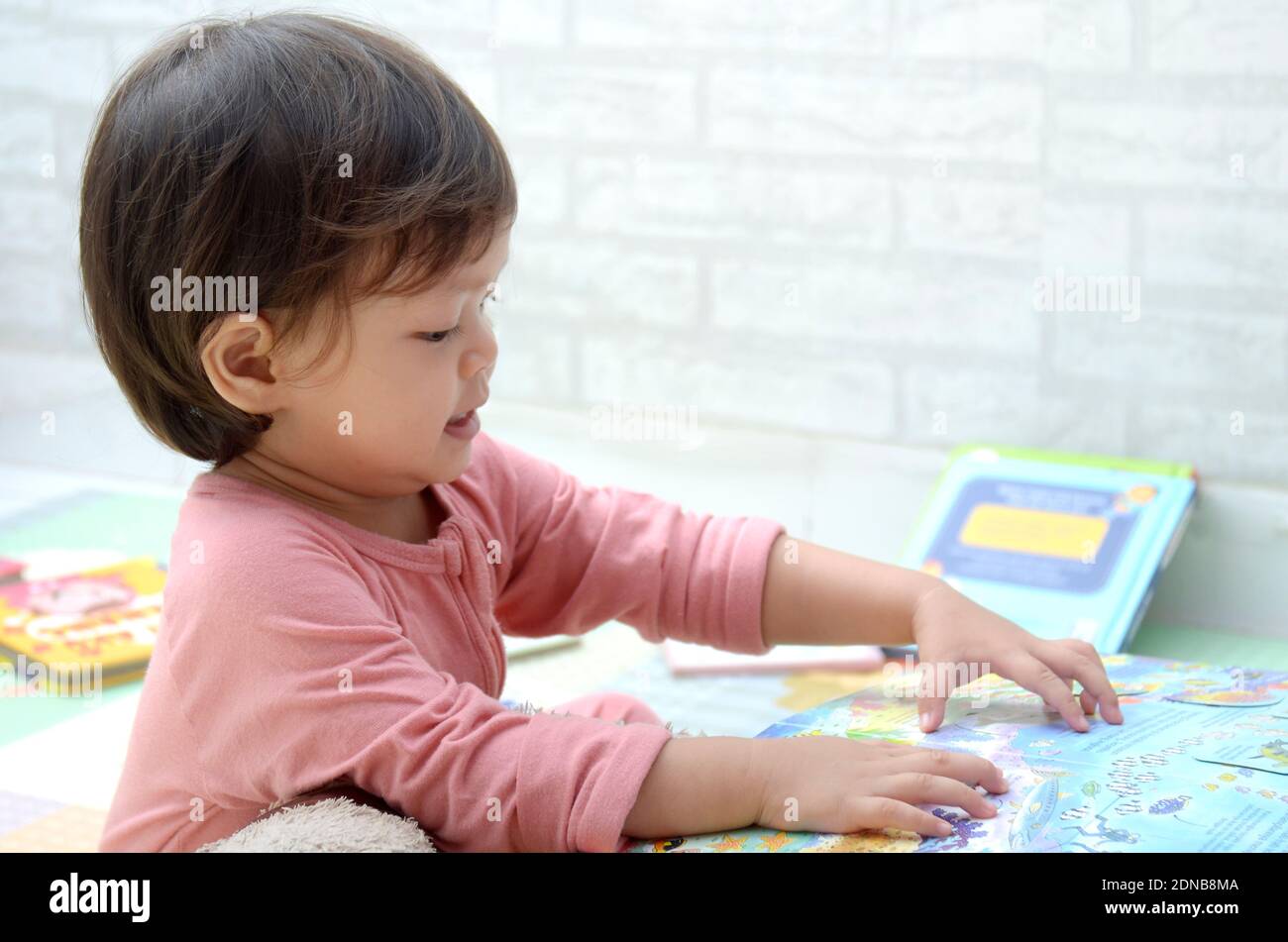 2 ans, todller, fille de bébé asiatique, jouant avec son livre.Reading un livre. Banque D'Images