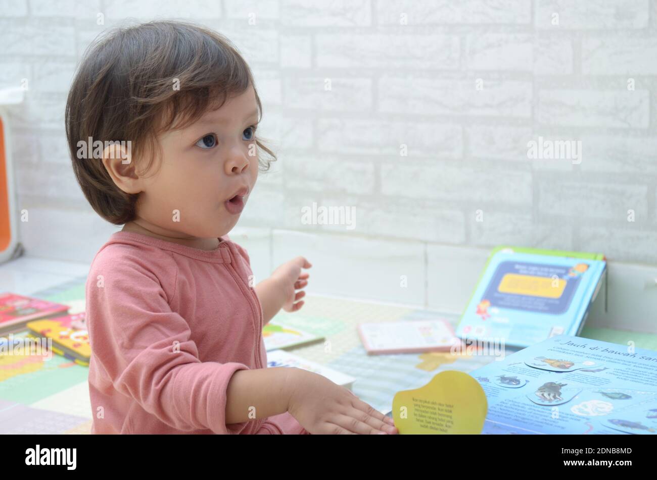 2 ans, todller, fille de bébé asiatique, jouant avec son livre.Reading un livre. Banque D'Images