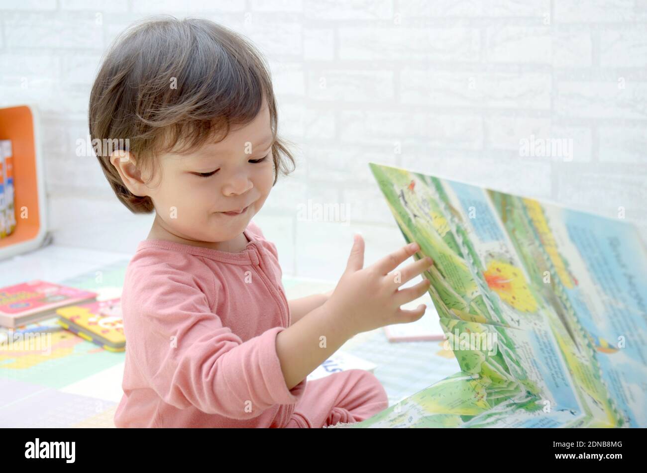 2 ans, todller, fille de bébé asiatique, jouant avec son livre.Reading un livre. Banque D'Images