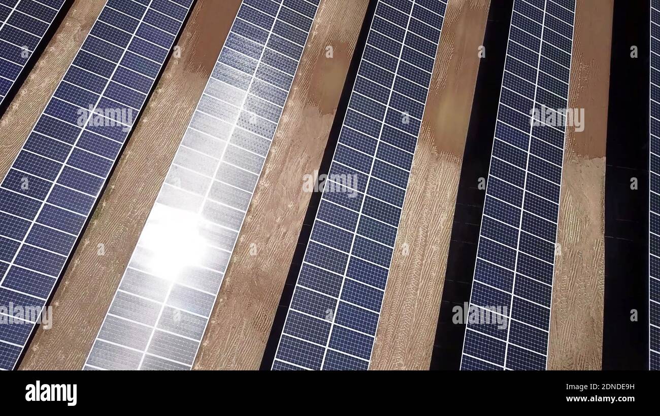 Réflexion de la lumière du soleil sur les panneaux d'énergie solaire dans le désert. Vue aérienne au-dessus de la vue des modules photovoltaïques en arrière-plan de la ferme de centrale d'énergie solaire Banque D'Images