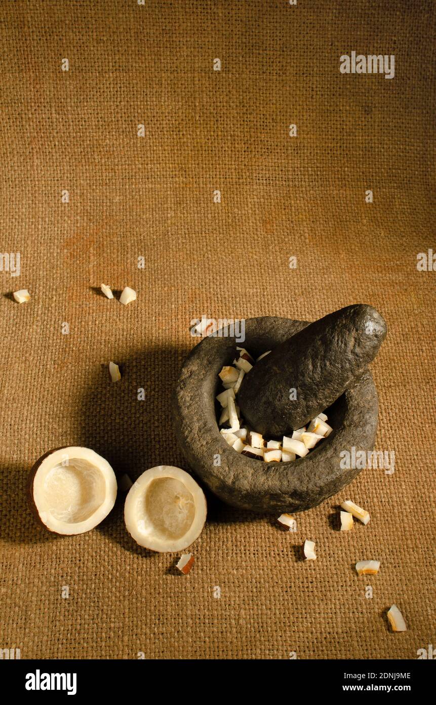 Pierre indienne Mortar et pilon ensemble avec des pièces de noix de coco séchées dans le mortier. Photo en studio Banque D'Images