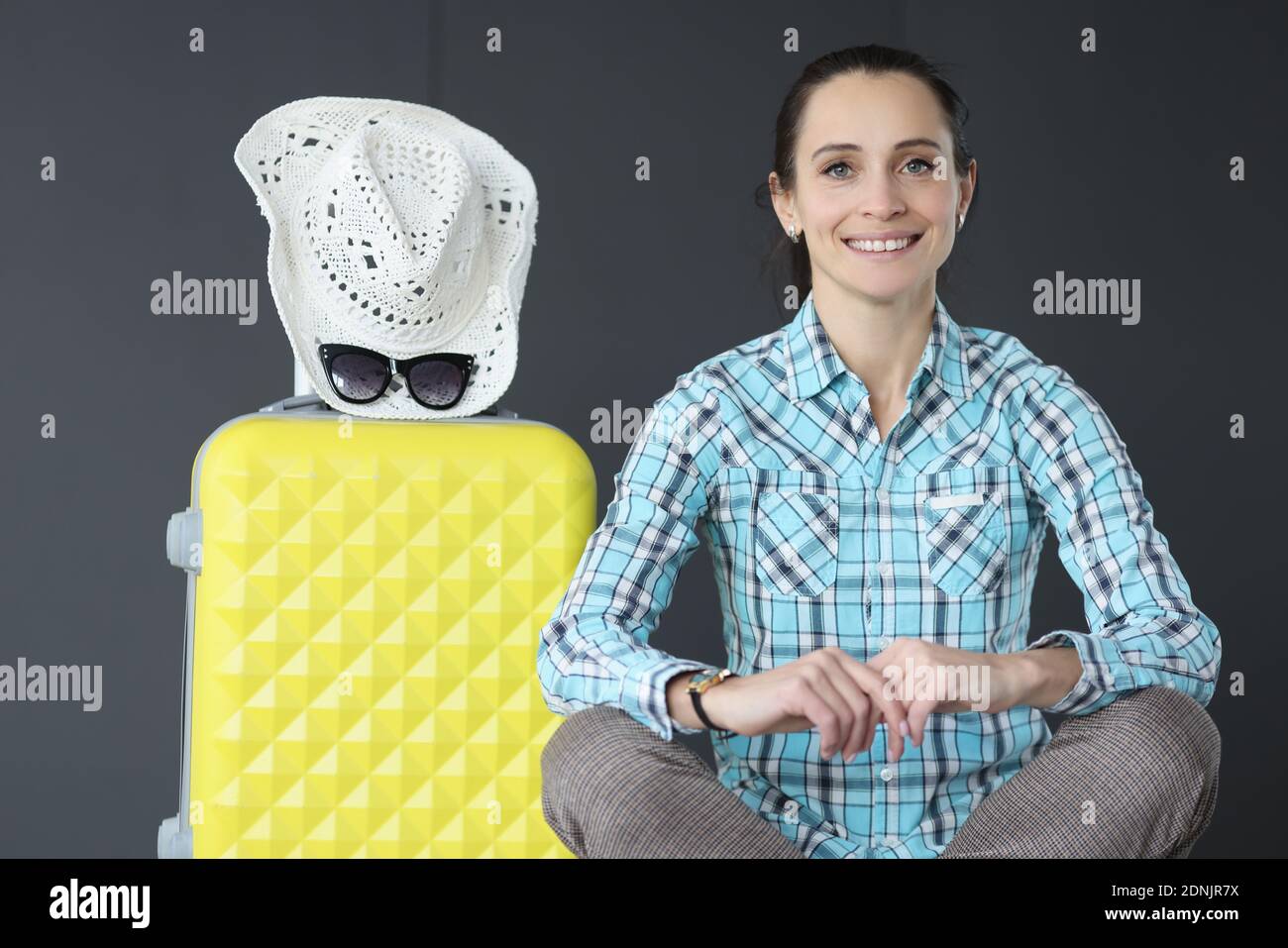 Portrait de la jeune femme avec une valise jaune et un chapeau Banque D'Images