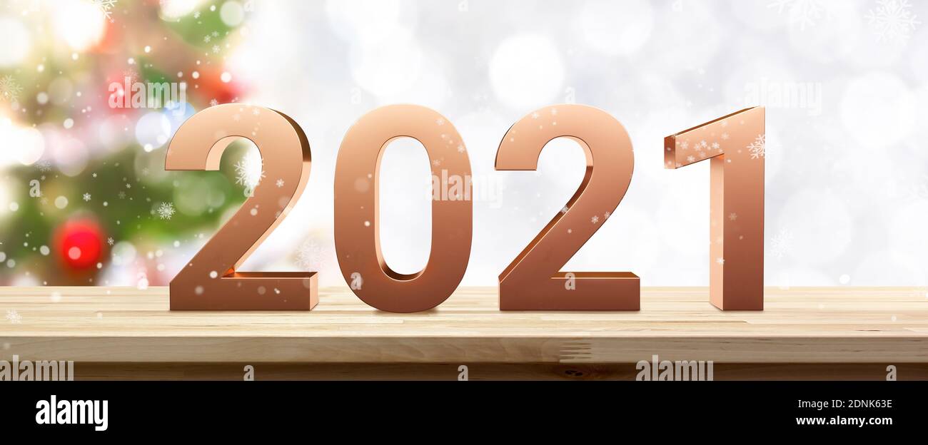 Couleur cuivre doré numéro 2021 sur table en bois avec sapin de noël flou et chute de neige sur fond de bannière Banque D'Images
