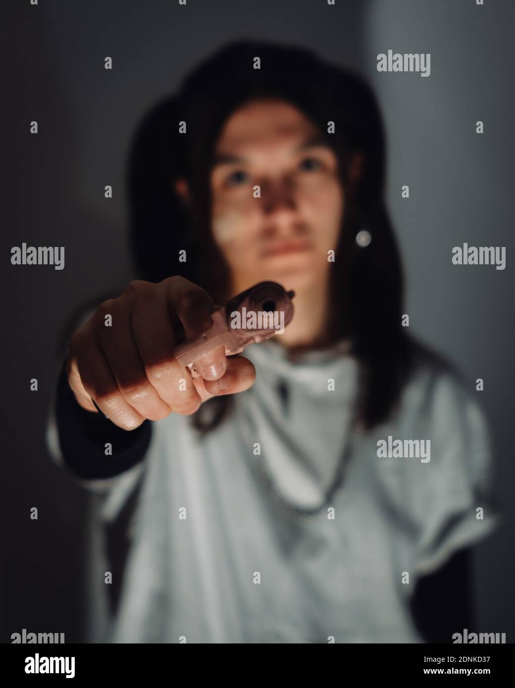 Un cliché sélectif de mise au point d'une jeune fille de gangster tenant un pistolet Banque D'Images