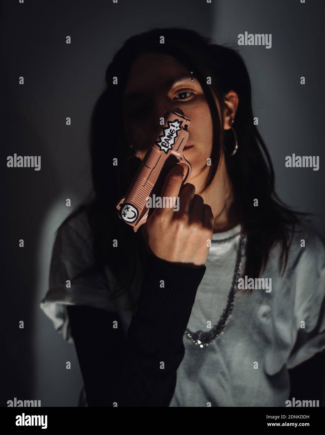 Un cliché sélectif de mise au point d'une jeune fille de gangster tenant un pistolet Banque D'Images