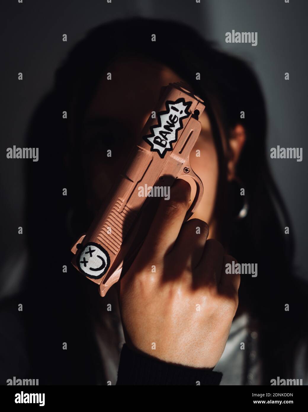 Un cliché sélectif de mise au point d'une jeune fille de gangster tenant un pistolet Banque D'Images