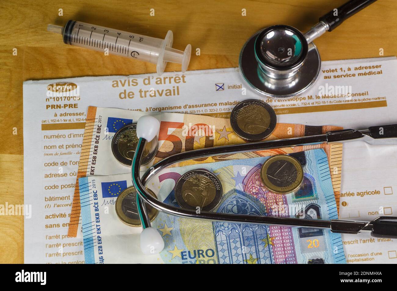 Avis d'arrêt de travail médical, seringue, stéthoscope noir, billets et pièces en euros Banque D'Images