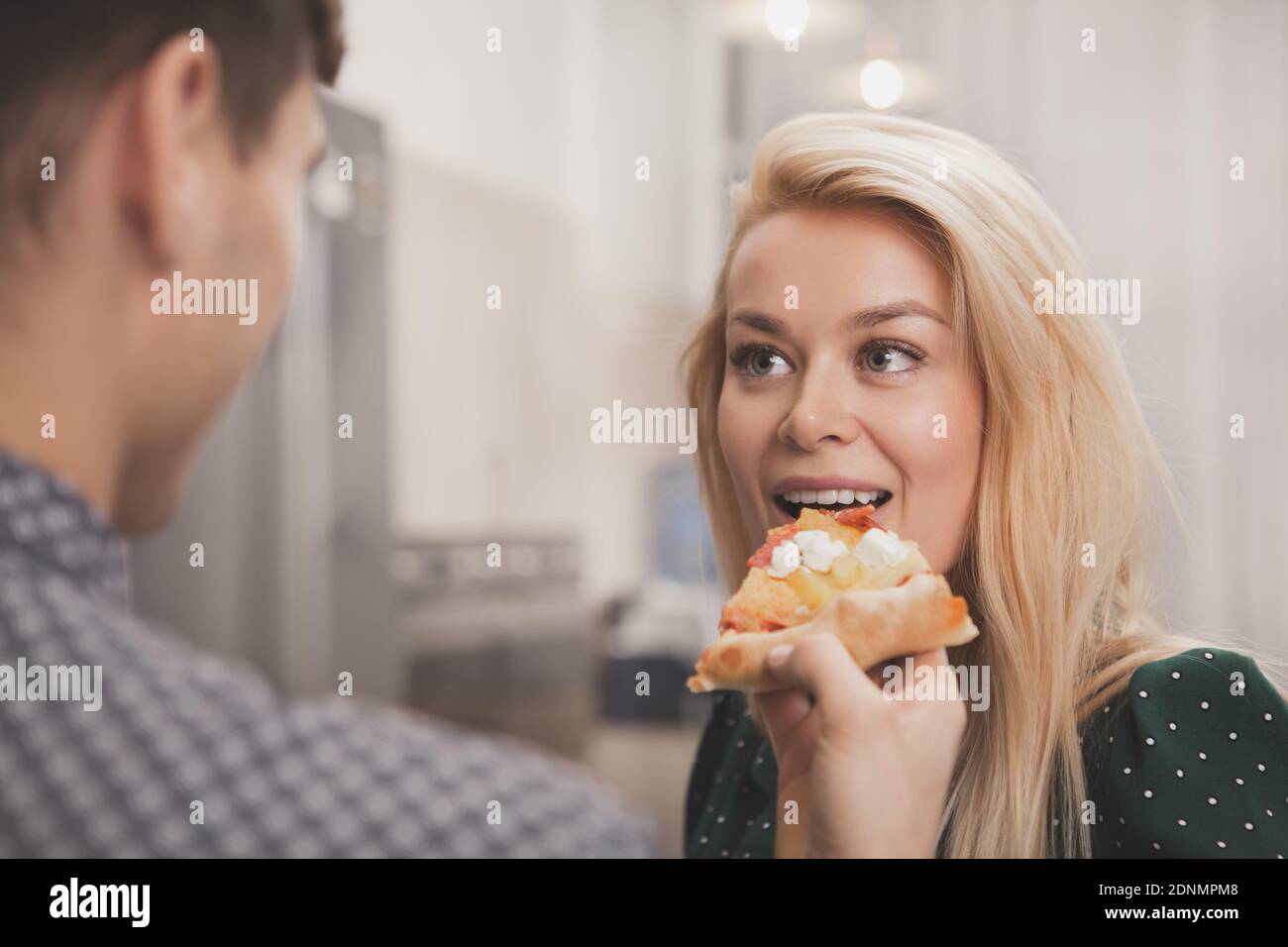 Belle jeune femme appréciant de piquer une délicieuse pizza, son petit ami affectueux l'offerng. Homme nourrissant de la pizza à sa belle femme. Couple heureux et aimant Banque D'Images