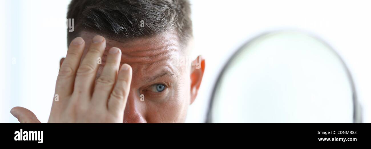 L'homme coiffe ses cheveux avec du gel devant le miroir. Banque D'Images