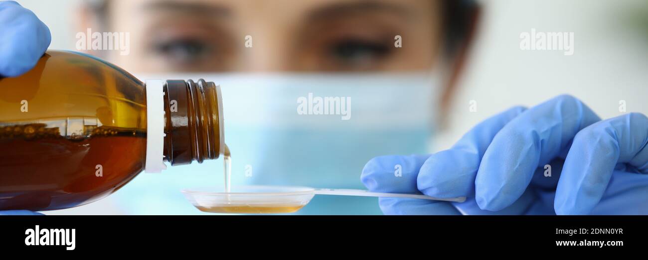 Le médecin verse des médicaments dans une cuillère de mesure Banque D'Images