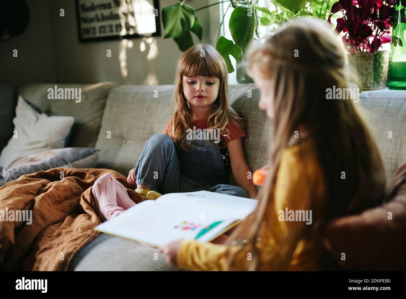 Sœurs lisant le livre sur le canapé Banque D'Images