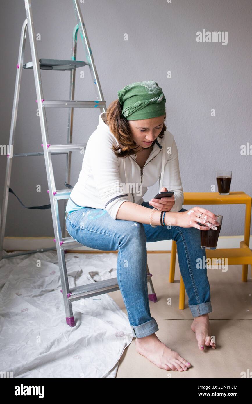 Femme utilisant le téléphone tout en prenant le café Banque D'Images