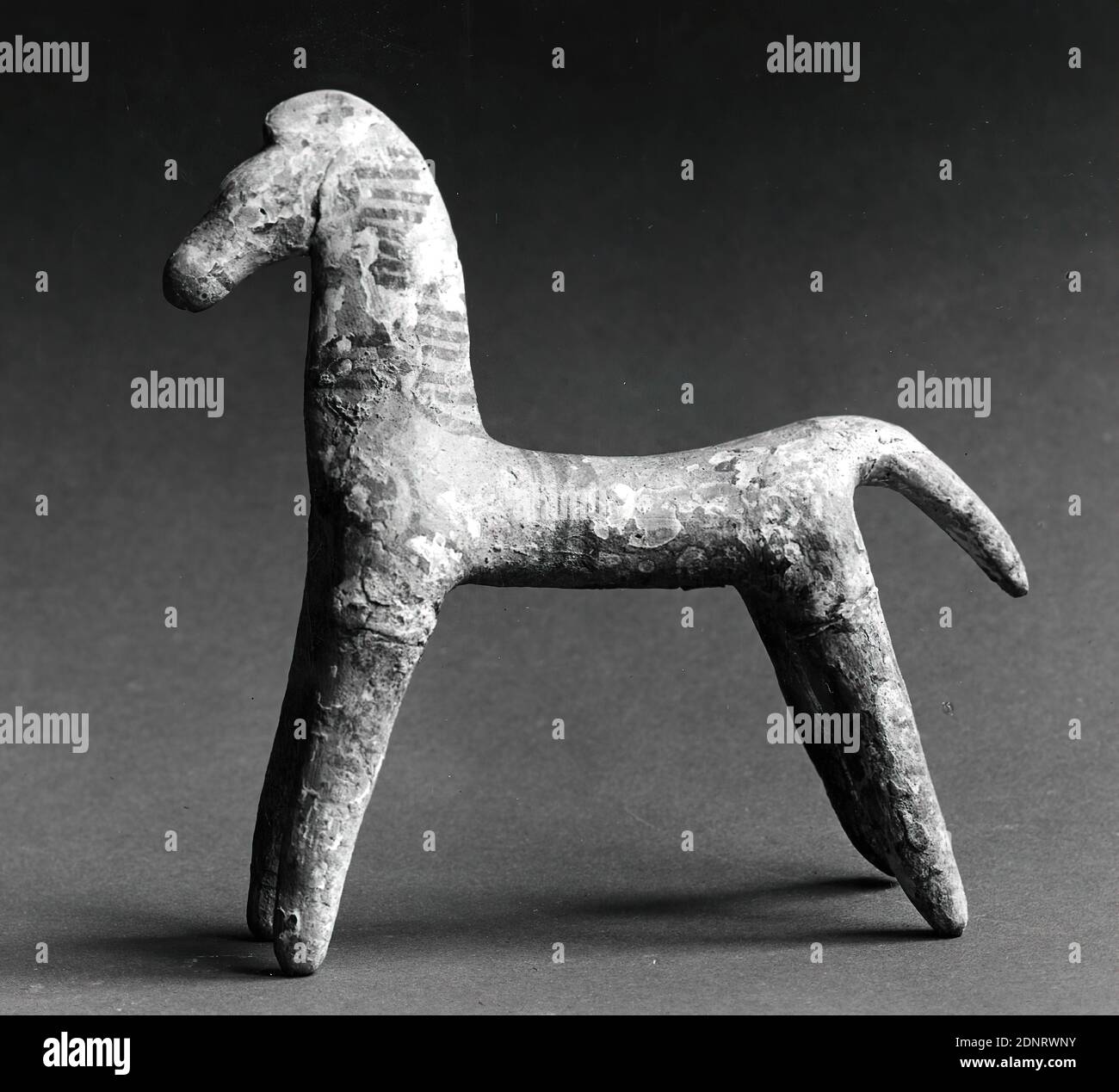 Cheval, anciennement Johannes W. F. Collection Reimers (Hambourg), argile, modélisée à la main, cuite (céramique), peinte (céramique), peinture froide, argile, Total: Hauteur: 13 cm; largeur: 13.3 cm; profondeur: 4.2 cm, céramique, petites sculptures/petites œuvres d'art, sculptures tridimensionnelles, articles de tombe, cheval, archaïque moyenne, antiquité grecque, élancé, cheval stylisé avec le cou et la tête aplatis sur les côtés. La queue est courte et aplatie comme une queue de beavertail. Les jambes évasées ne sont pas articulées. Le cou est peint avec des lignes parallèles transversales; trois lignes circulaires s'exécutent autour du tronc. Banque D'Images
