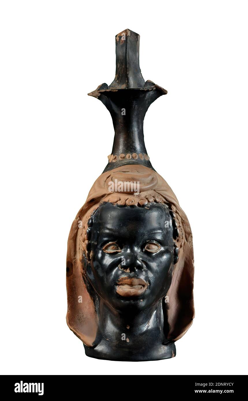 Peintre Hasselmann, carafe en forme de tête africaine, argile, rapidement transformée, pressée en forme, modélisée à la main, argile, tournée et modélisée à la main, total: Hauteur: 15.1 cm; largeur: 5.5 cm; profondeur: 6.7 cm; hauteur: 12.5 cm (sans poignée), céramique, types de personnes, image de tête, africain, classicisme tardif (antiquité grecque), la carafe a un col mince, haut avec bec de trèfle et une poignée haute. Ces parties sont vernies en noir à l'extérieur et à l'intérieur; autour de l'extrémité inférieure du cou se trouve une frise en perles légères. Le ventre de la carafe est formé par la tête, qui est reproduite jusqu'à l'épaule Banque D'Images