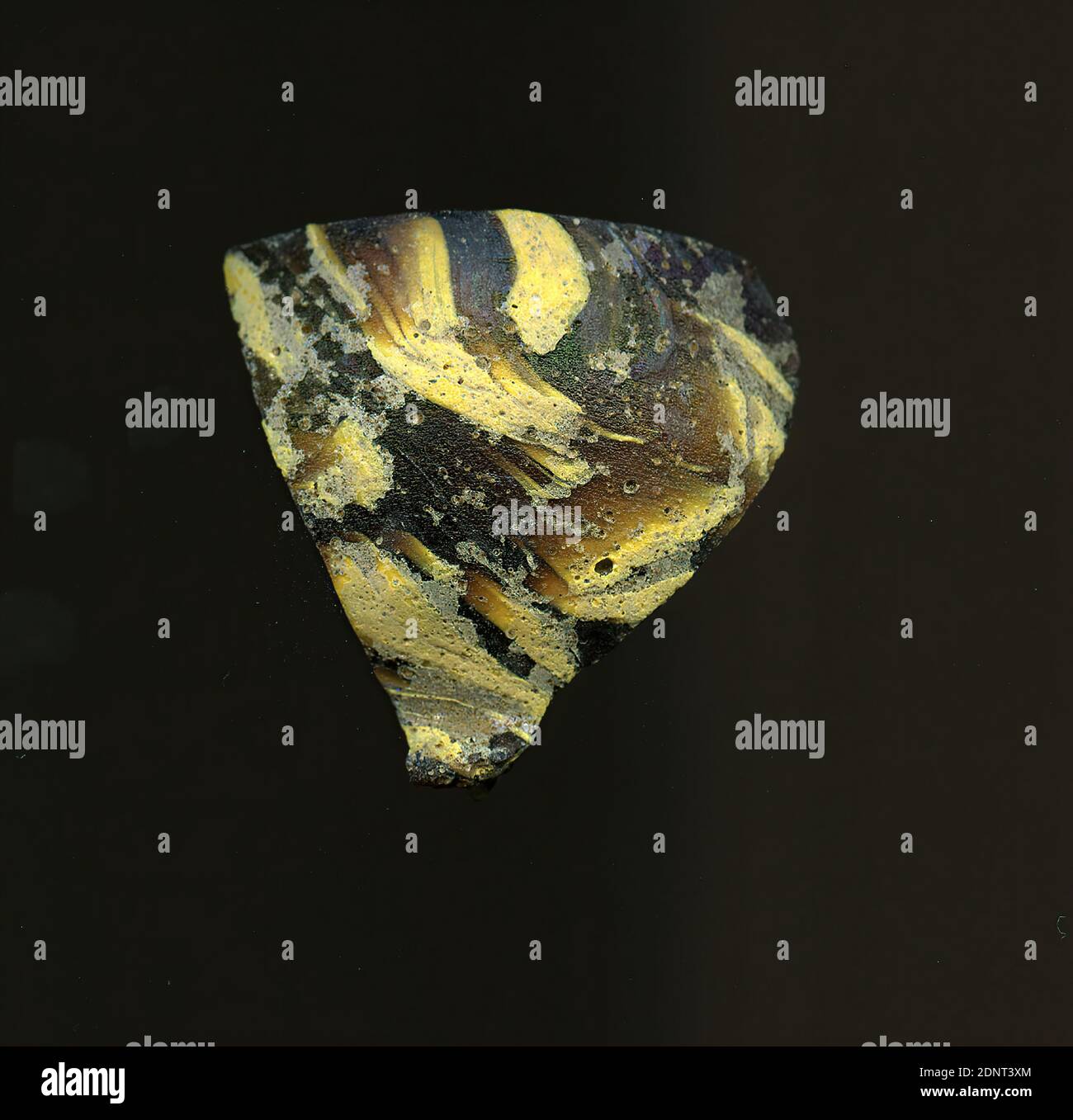 Fragment d'un vaisseau, verre, pressé, coupé, Total: Hauteur: 3.60 cm; largeur: 3.20 cm, début de la période impériale, UNE légère courbure du fragment de verre permet l'attribution à un vaisseau, éventuellement un bol. Dans le verre brun, plusieurs bandes jaunâtres et grisâtres sont irrégulièrement visibles. De l'autre côté, il y a un point rouge pour la production différents verres de couleur ont été formés en tubes et tiges. Ils ont été pressés ensemble et chauffés, ce qui a donné une longue tige. Le verre maintenant coupé en tranches avait des motifs amorphes ou floraux différents. Banque D'Images