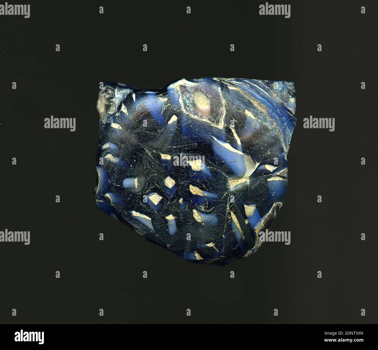 Fragment d'un vaisseau, verre, pressé, coupé, Total: Hauteur: 4.10 cm; largeur: 2.20 cm, début de la période impériale, UNE légère courbure du fragment de verre permet l'attribution à un vaisseau, éventuellement un bol ou une bouteille. Le verre bleu foncé est parsemé de différentes formes géométriques blanches telles que de petits carrés, des points angulaires ou des cercles. À ces formes, le verre est bleu clair. Pour la production, des verres de différentes couleurs ont été formés en tubes et en tiges. Ils ont été pressés ensemble et chauffés, ce qui a donné une longue tige. Le verre maintenant coupé en tranches avait des motifs amorphes ou floraux différents. Banque D'Images