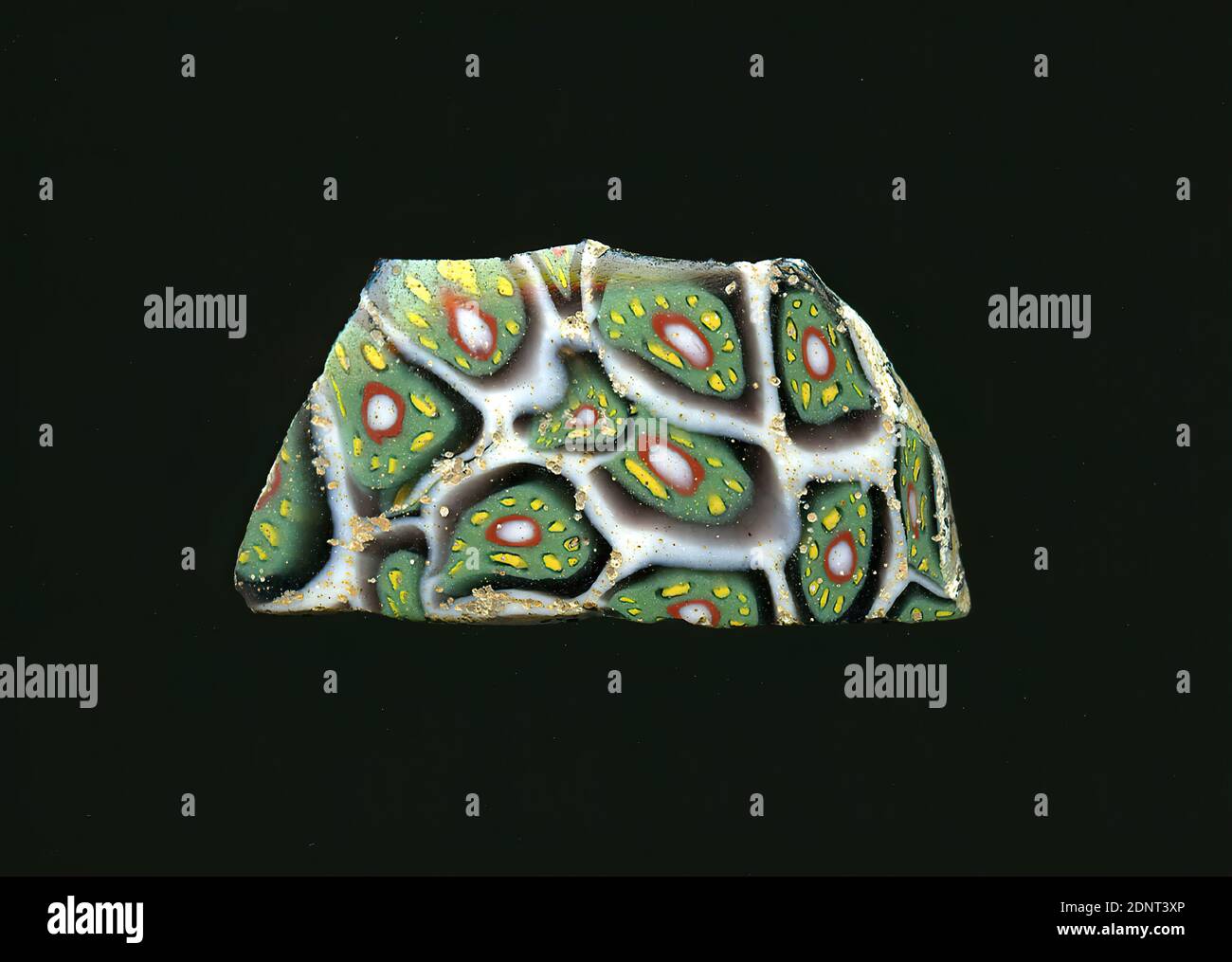 Fragment d'un vaisseau, verre, technique millefiori, Total: Hauteur: 3.30 cm; largeur: 1.70 cm, conteneur, stockage, travail de cuisine, ornements floraux, période impériale précoce, UNE légère courbure du fragment de verre permet l'affectation à un vaisseau, éventuellement un bol. À l'intérieur d'un réseau de lignes blanches en nid d'abeille, une fleur est visible dans chacune des techniques de millefiori. Autour d'un noyau blanc avec un contour rouge, des points jaunes sont visibles dans une bande verte. L'espace entre la fleur et le nid d'abeille blanc est violet. Pour la production, des verres de différentes couleurs ont été formés en tubes et en tiges. Banque D'Images