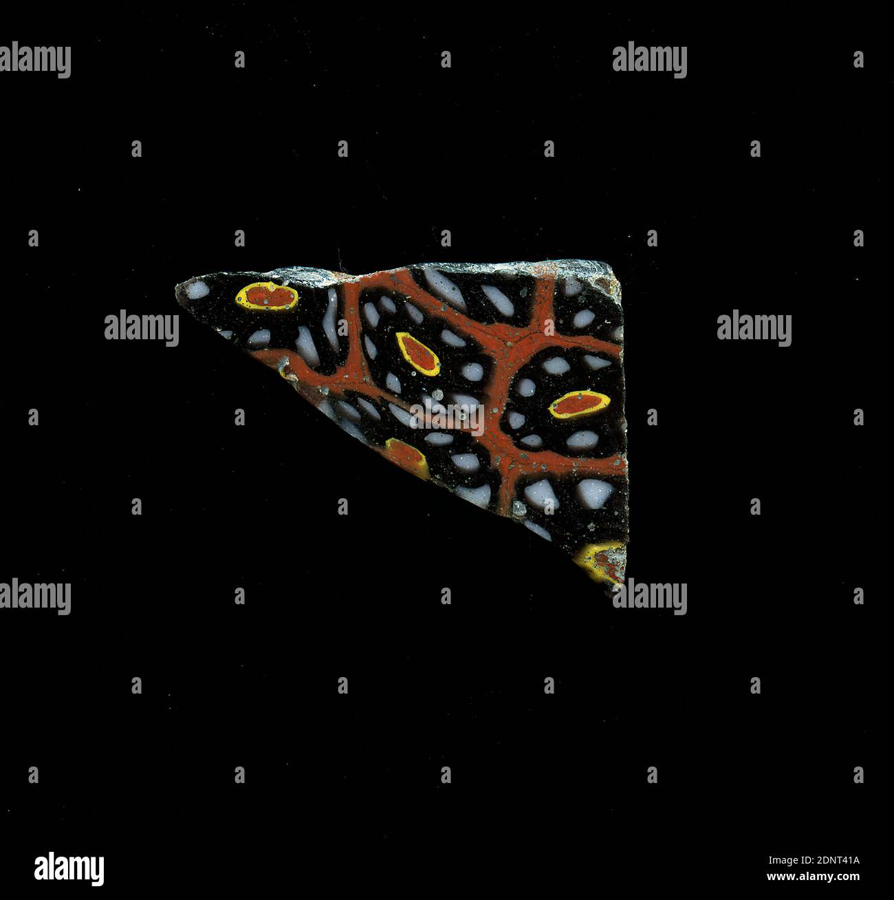 Fragment d'un vaisseau, verre, technique millefiori, Total: Hauteur: 2.50 cm; largeur: 1.90 cm, conteneur, stockage, travail de cuisine, ornements floraux, période impériale précoce, UNE légère courbure du fragment de verre permet d'assigner à un vaisseau, éventuellement un bol. Plusieurs fleurs de la technique millefiori peuvent être vues sur fond rouge. Autour d'un noyau rouge avec contour jaune, des points blancs avec contour noir sont placés sous forme de pétales. Pour la production, des verres de différentes couleurs ont été formés sur des tubes et des tiges. Ils ont été pressés ensemble et chauffés, ce qui a donné une longue tige. Banque D'Images