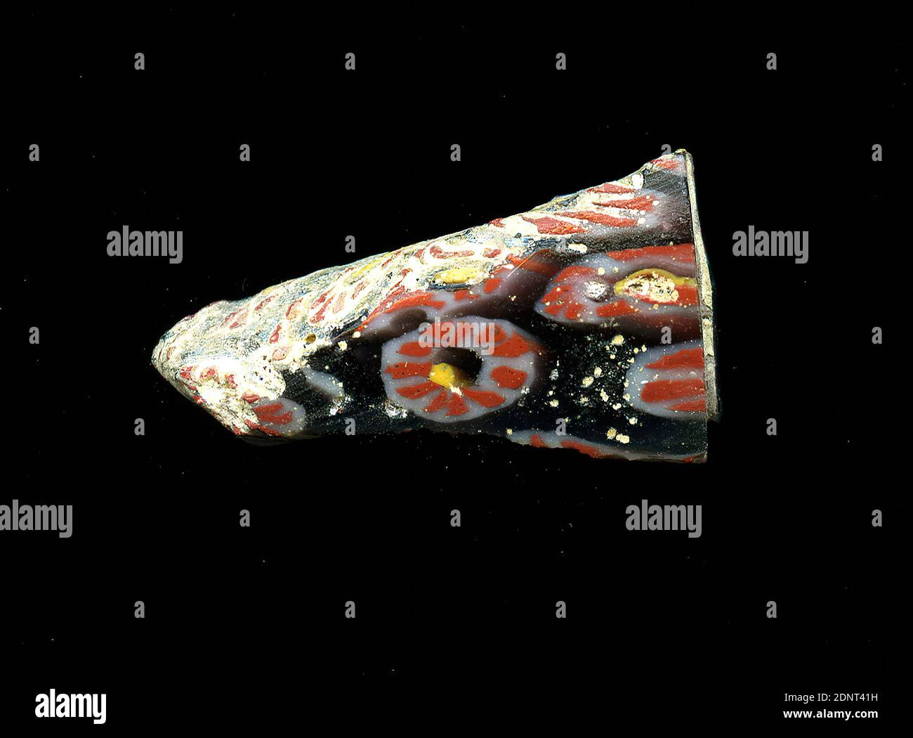 Fragment d'un vaisseau, verre, technique millefiori, Total: Hauteur: 2.20 cm; largeur: 1.20 cm, conteneur, stockage, travail de cuisine, ornements floraux, période impériale précoce, UNE légère courbure du fragment de verre permet l'affectation à un vaisseau, éventuellement un bol. Plusieurs fleurs sont représentées sur fond noir dans la technique de millefiori. Une bande blanche est placée autour d'un point jaune, dans lequel plusieurs lignes rouges représentent les pétales selon un motif radial. Pour la production, des verres de différentes couleurs ont été formés sur des tubes et des tiges. Ils ont été pressés ensemble et chauffés, ce qui a donné une longue tige. Banque D'Images