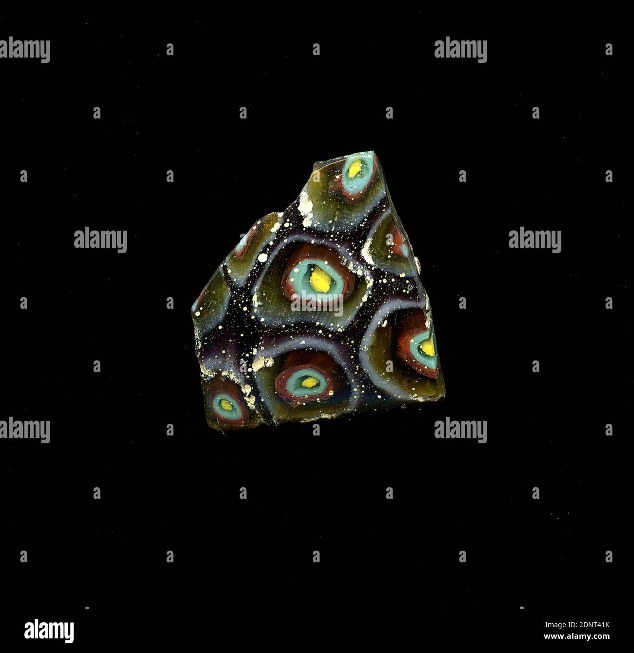 Fragment d'un vaisseau, verre, technique millefiori, Total: Hauteur: 1.90 cm; largeur: 2.40 cm, conteneur, stockage, travail de cuisine, ornements de fleurs, période impériale précoce, UNE légère courbure du fragment de verre permet l'affectation à un vaisseau, éventuellement un bol. Plusieurs fleurs sont représentées sur fond violet dans la technique de millefiori. Ils se composent d'un cercle jaune comme noyau, autour duquel plusieurs anneaux de couleur sont disposés de manière concentrique - de l'intérieur à l'extérieur en transparent, vert menthe, rouge, marron, blanc. Pour la production, des verres de différentes couleurs ont été formés en tubes et en tiges. Banque D'Images