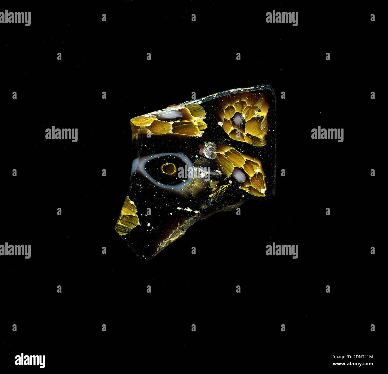 Fragment d'un vaisseau, verre, technique millefiori, Total: Hauteur: 2.50 cm; largeur: 2.00 cm, conteneur, stockage, travail de cuisine, ornements floraux, période impériale précoce, UNE légère courbure du fragment de verre permet l'affectation à un vaisseau, éventuellement un bol. Sur fond violet, les formes de fleurs sont représentées dans la technique de millefiori. L'une consiste en anneaux concentriques dans la séquence de couleurs transparent, jaune, violet et blanc. L'autre consiste en un noyau blanc avec un contour violet, autour duquel les points circulaires transparents avec un contour jaune sont disposés de manière transparente sous forme de pétales. Banque D'Images