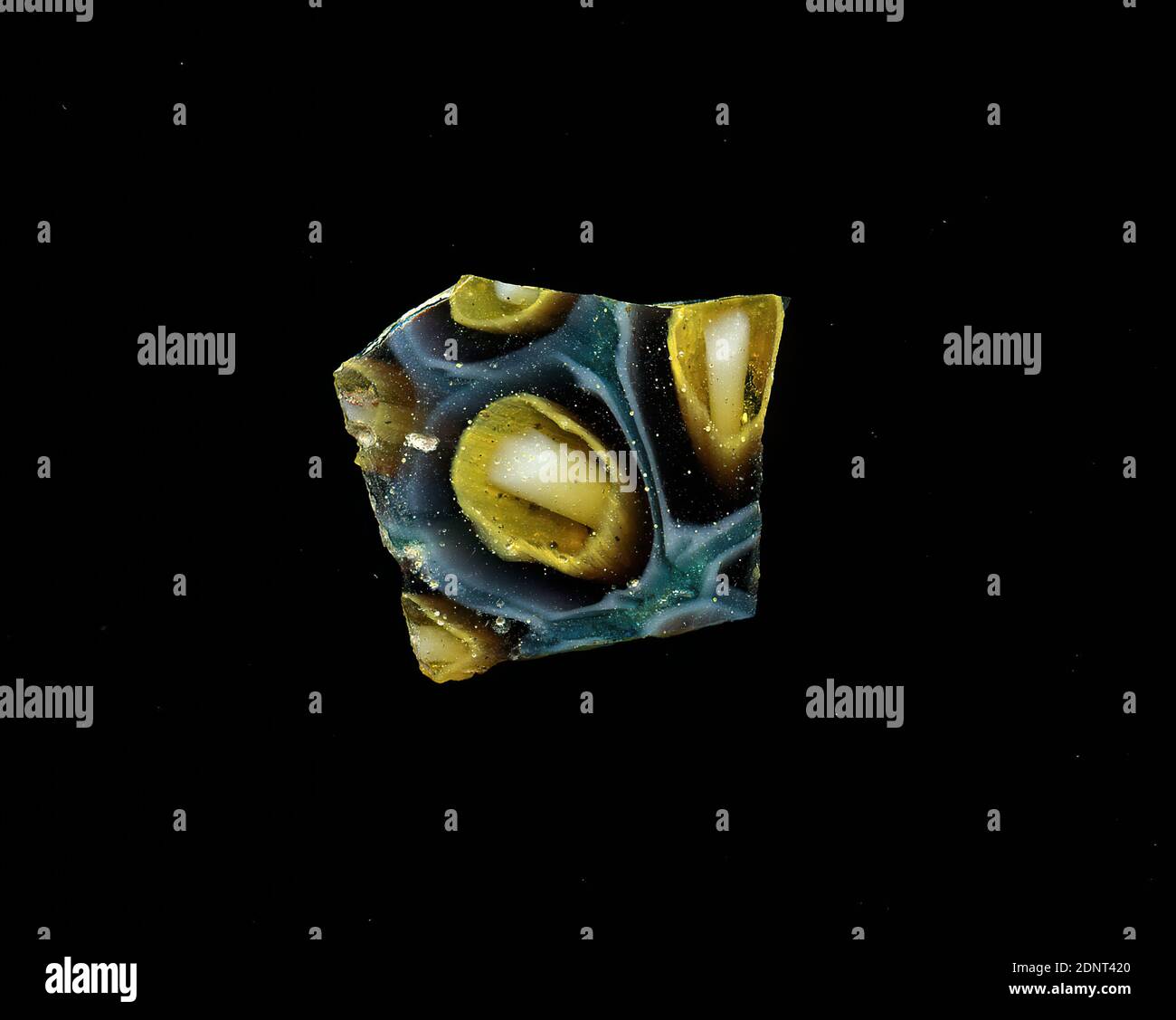 Fragment d'un vaisseau, verre, technique millefiori, Total: Hauteur: 1.60 cm; largeur: 1.40 cm, ornements floraux, début de la période impériale, UNE légère courbure du fragment de verre permet l'attribution à un vaisseau, éventuellement un bol plusieurs fleurs stylisées sont représentées sur un fond bleu. Autour d'un point blanc comme le noyau sont des couronnes de verre transparent, jaune, violet et blanc de l'intérieur à l'extérieur. Pour la production, des verres de différentes couleurs ont été formés en tubes et en tiges. Ils ont été pressés ensemble et chauffés, ce qui a donné une longue tige. Banque D'Images