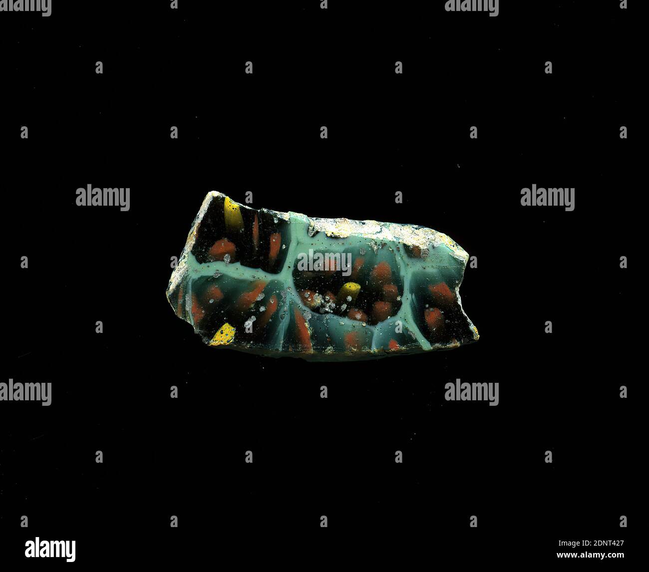 Fragment d'un vaisseau, verre, technique millefiori, Total: Hauteur: 2.20 cm; largeur: 1.10 cm, conteneur, stockage, travail de cuisine, ornements de fleurs, période impériale précoce, UNE légère courbure du fragment de verre permet l'affectation à un vaisseau, éventuellement un bol. Le shard vert menthe montre plusieurs fleurs dans la technique de millefiori. Un cercle jaune est entouré de plusieurs cercles rouges avec des contours noirs. Les images sont légèrement déformées. Pour la production, des verres de différentes couleurs ont été formés en tubes et en tiges. Ils ont été pressés ensemble et chauffés, ce qui a donné une longue tige. Banque D'Images