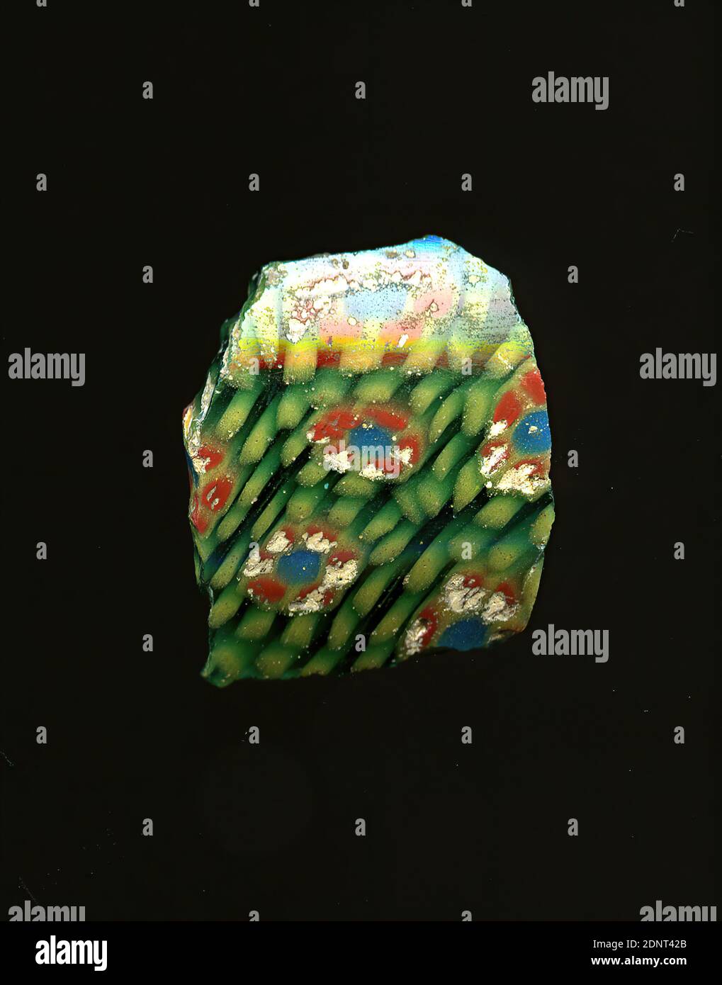 Fragment de vaisseau, verre, technique millefiori, Total: Hauteur: 1.90 cm; largeur: 2.20 cm, contenant, stockage, cuisine, boisson et vaisselle, ornements floraux, période impériale précoce, période impériale moyenne, période impériale tardive, UNE légère courbure du fragment de verre permet l'attribution à un vaisseau, éventuellement un bol le shard vert montre plusieurs fleurs en technique de millefiori. Autour d'un point bleu avec un contour jaune, des points rouges encadrés jaunes sont attachés sous forme de pétales. Ils sont entourés de points jaunes sur des lignes circulaires. Banque D'Images