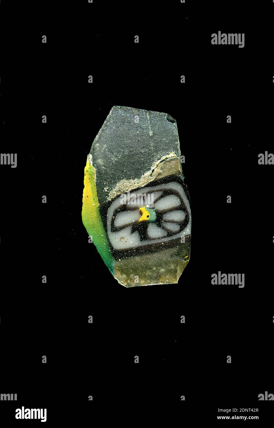 Fragment d'un vaisseau, verre, technique millefiori, Total: Hauteur: 1.20 cm; largeur: 2.00 cm, conteneur, stockage, travail de cuisine, ornements de fleurs, période impériale précoce, UNE légère courbure du fragment de verre permet l'affectation à un vaisseau, éventuellement un bol. Le shard de verre transparent montre une fleur dans la technique de millefiori au centre. Une bande verte et une bande jaune forment le cœur de la fleur. Autour de lui, plusieurs points blancs marquent les pétales. Un contour violet entoure l'ornement, autour duquel un autre blanc et un cadre violet sont placés. Banque D'Images