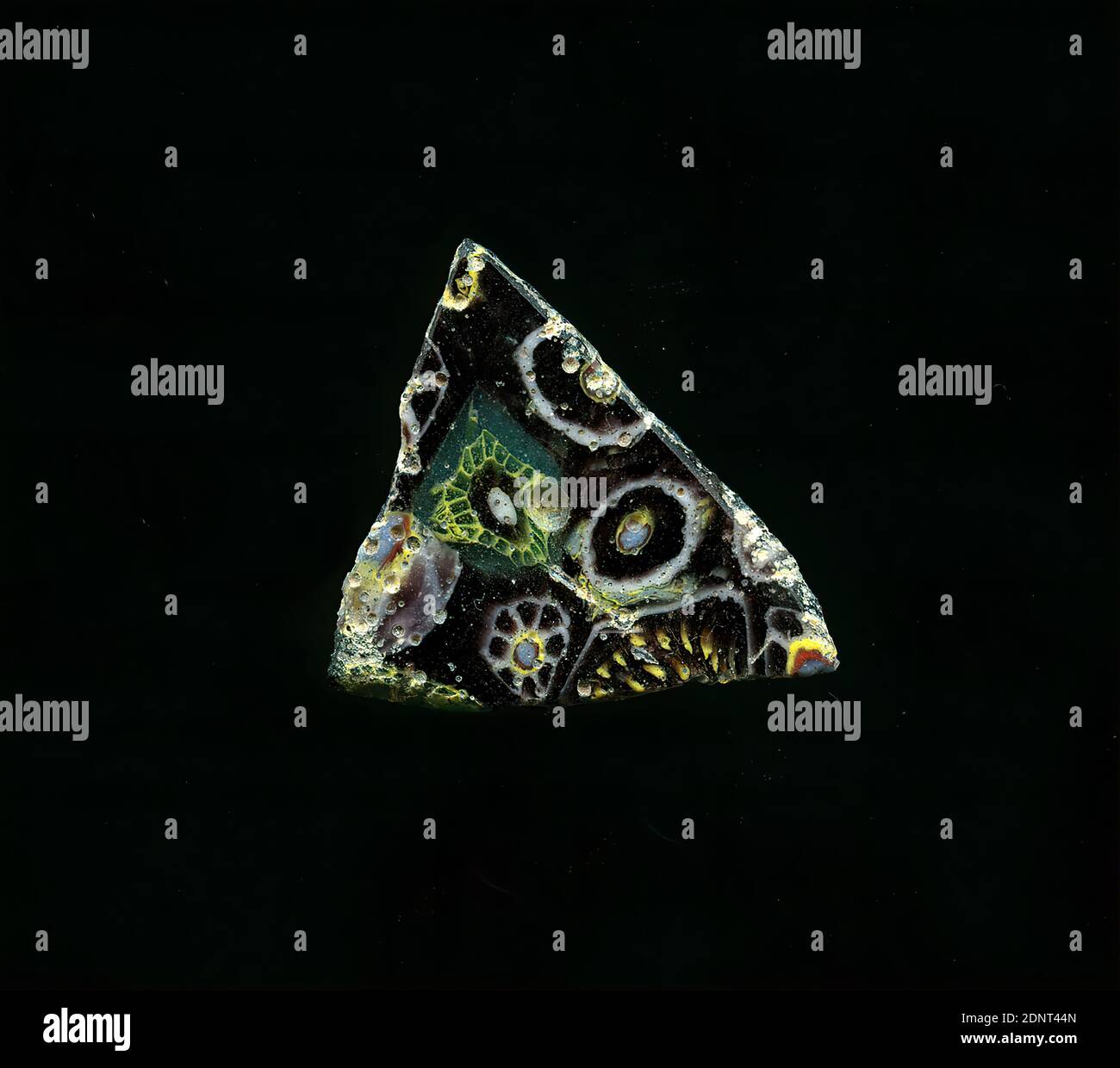 Fragment d'un vaisseau, verre, technique millefiori, Total: Hauteur: 2.20 cm; largeur: 2.00 cm, conteneur, stockage, travail de cuisine, ornements floraux, période impériale précoce, UNE légère courbure du fragment de verre permet l'affectation à un vaisseau, éventuellement un bol. Divers types de fleurs dans la technique de millefiori peuvent être vus sur fond violet. Un type consiste en anneaux concentriques autour d'un point blanc avec des contours rouges et jaunes, autour desquels sont disposés un cercle violet et un cercle blanc; le second consiste en un point blanc avec des contours rouges et jaunes, autour duquel sont disposés les pétales à bords blancs. Banque D'Images