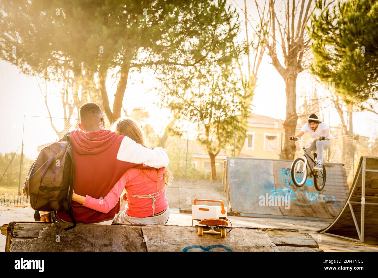 Vue arrière du jeune couple assis au parc Skateboard au coucher du soleil Banque D'Images