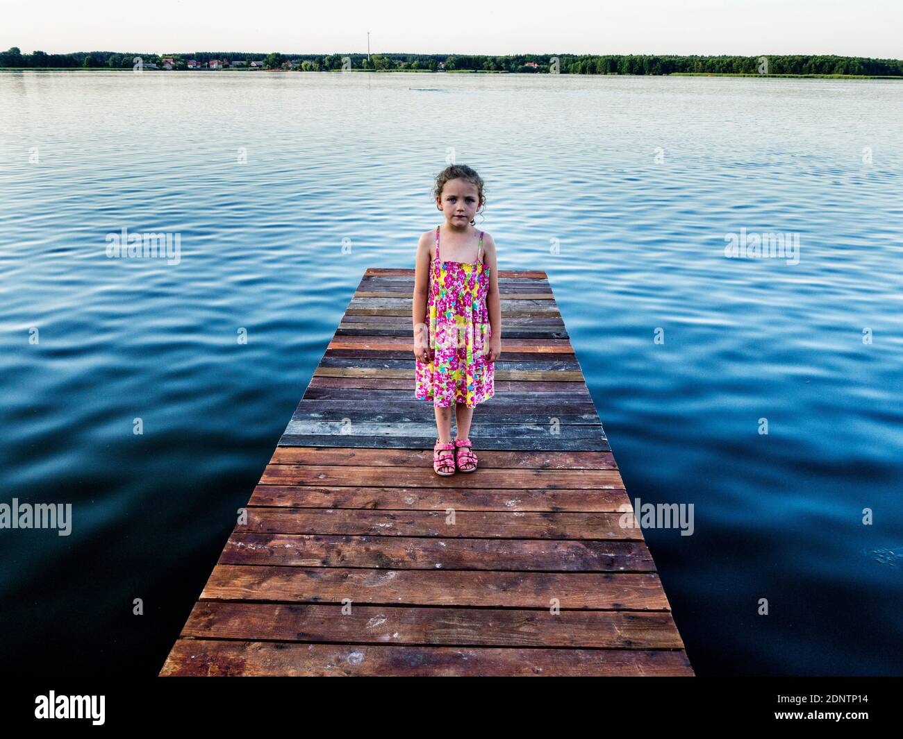Fille debout sur un quai en bois à un lac, Pologne Banque D'Images