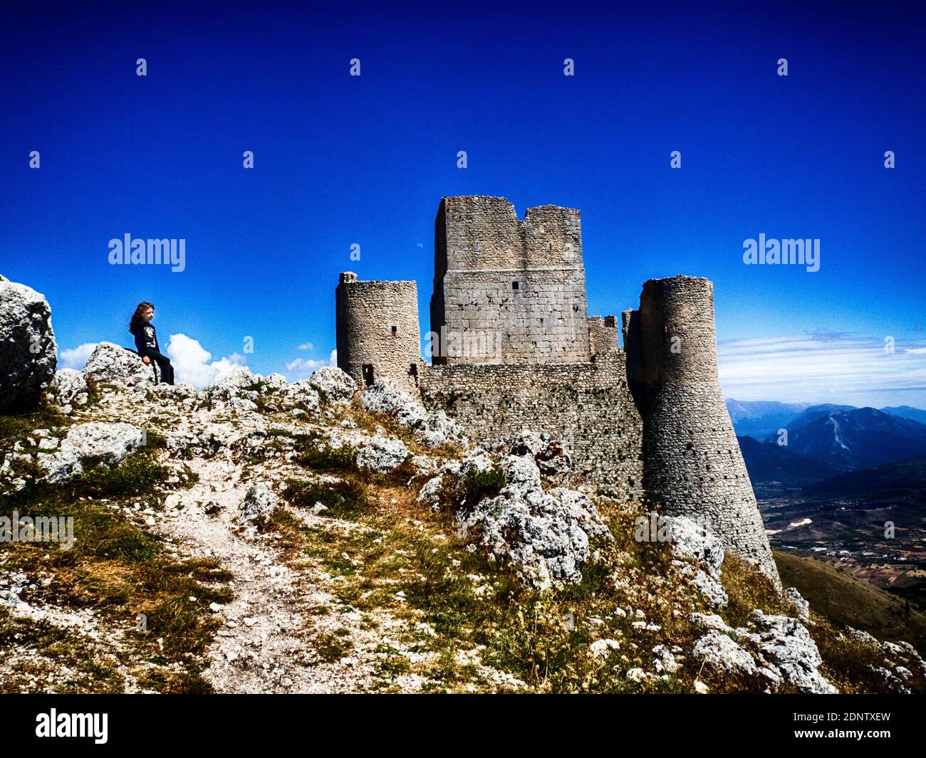 Fille assise sur des rochers par Rocca Calascio, l'Aquila, Abruzzes, Italie Banque D'Images
