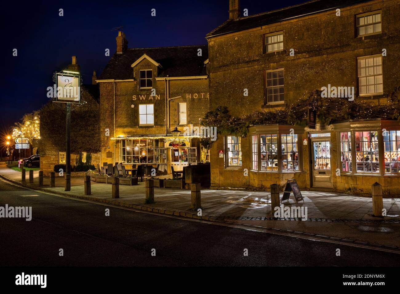 Royaume-Uni, Gloucestershire, Broadway, The Green, Swan Hotel et Cheltenham House magasin d'antiquités illuminé pour le village fin de nuit shopping de Noël Banque D'Images