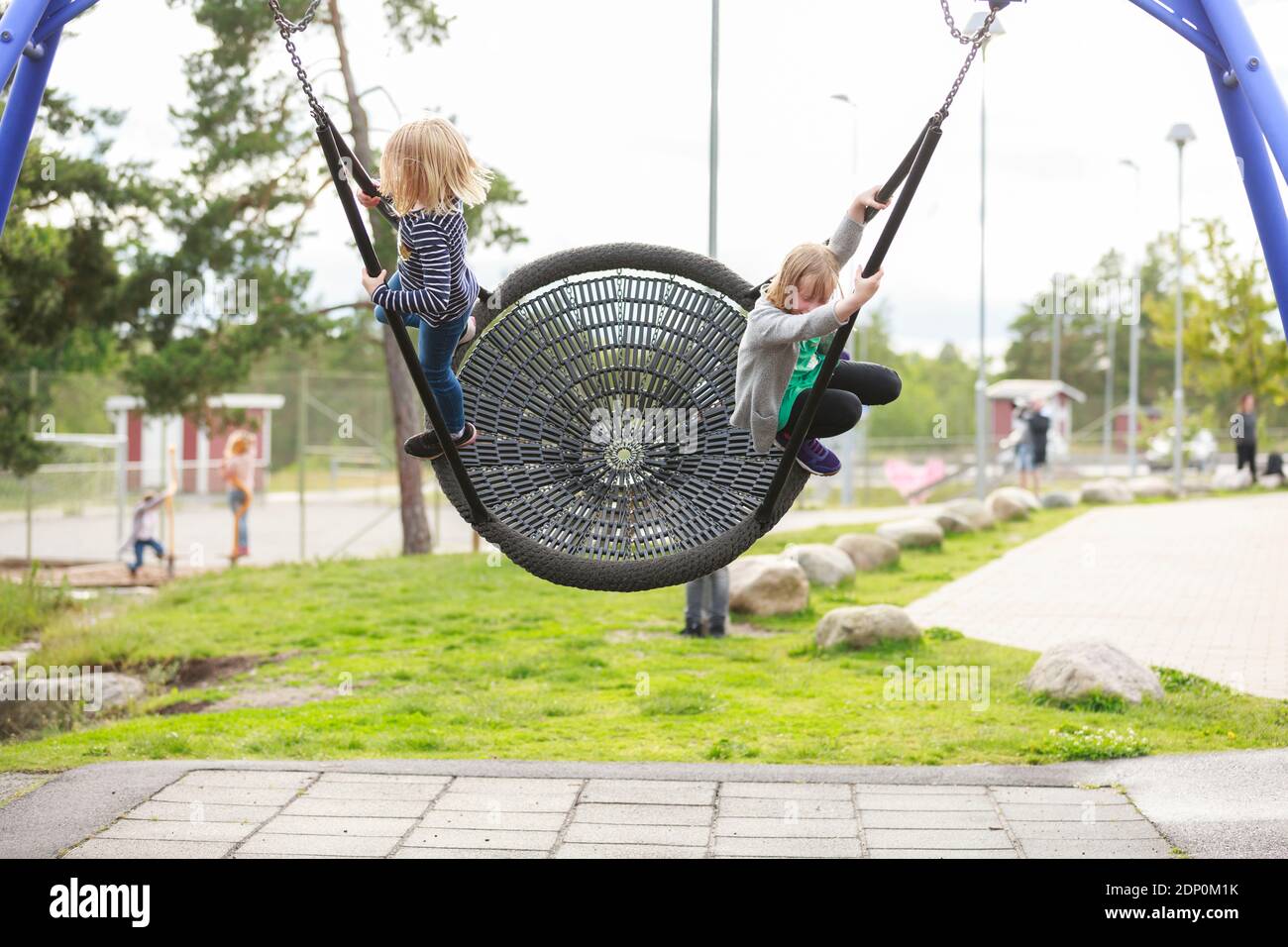 Les filles se balançant sur l'aire de jeux Banque D'Images