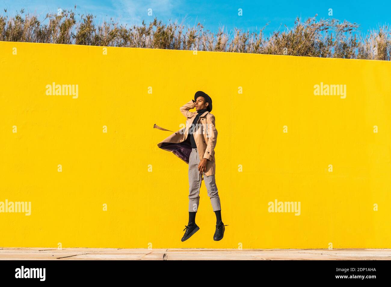 Jeune homme danser devant mur jaune, jumping mid air Banque D'Images