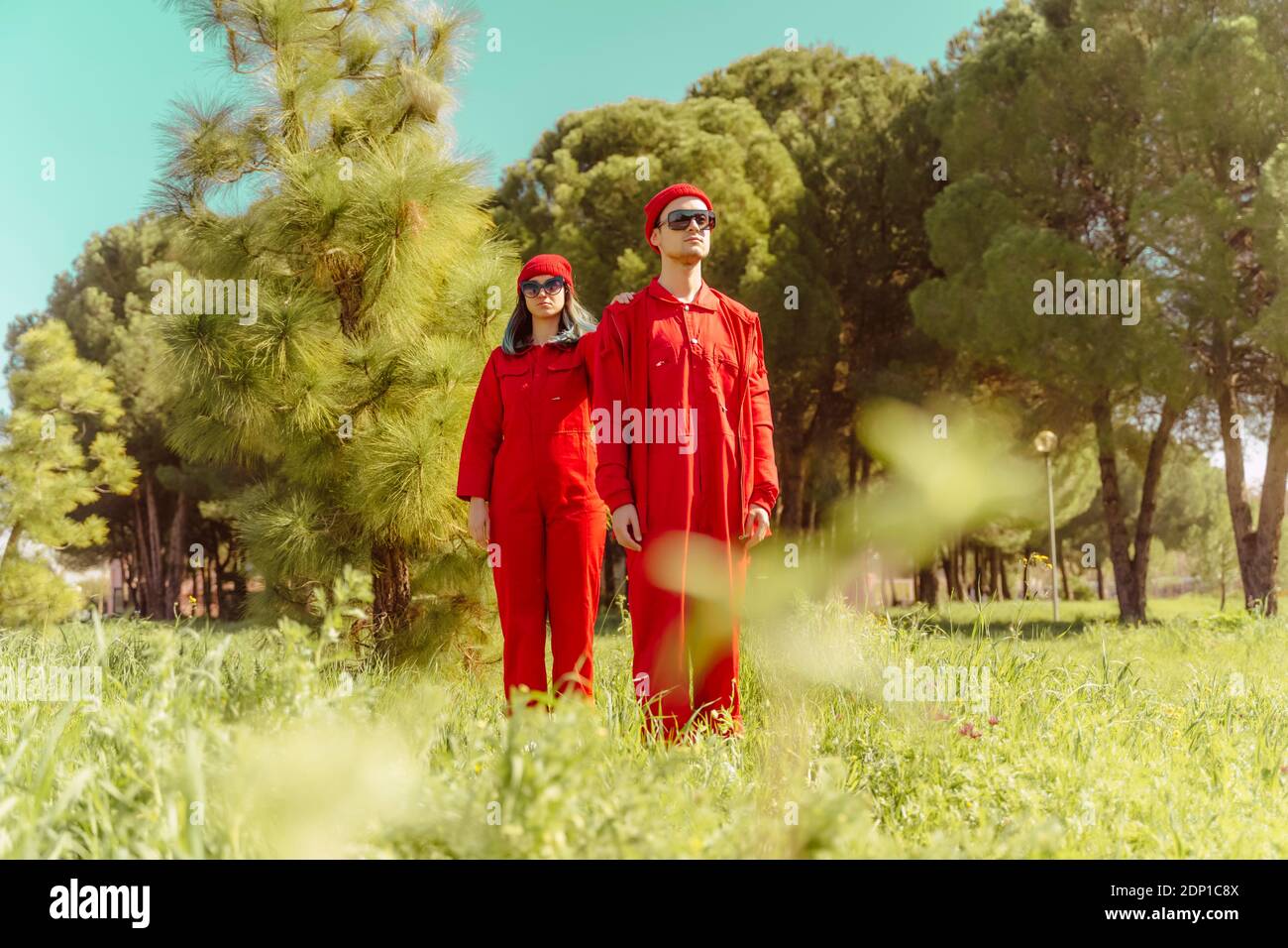 Jeune couple portant une combinaison rouge et des chapeaux debout dans la nature Banque D'Images