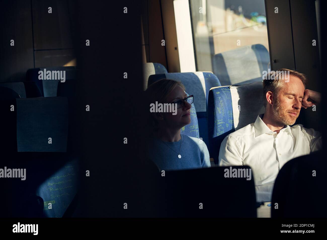 Homme assis dans le train avec les yeux fermés Banque D'Images